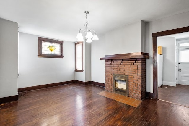 unfurnished living room with a wealth of natural light, dark hardwood / wood-style floors, a chandelier, and a fireplace