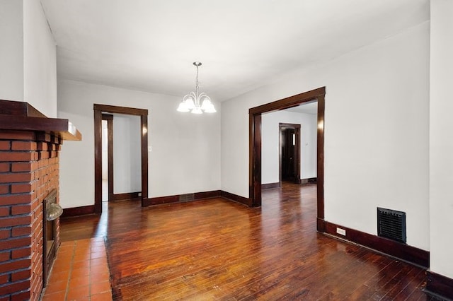 unfurnished dining area featuring dark hardwood / wood-style floors, a fireplace, and a chandelier