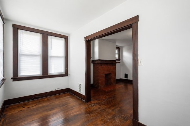 interior space with a fireplace, dark wood-type flooring, and plenty of natural light