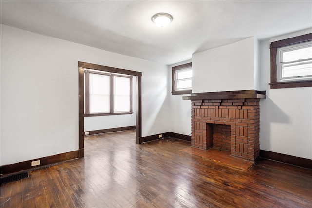 unfurnished living room featuring dark hardwood / wood-style floors and a brick fireplace