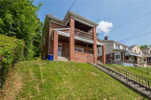 back of house featuring a lawn and a balcony