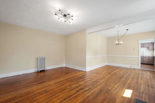 empty room featuring a chandelier, hardwood / wood-style flooring, radiator, and sink