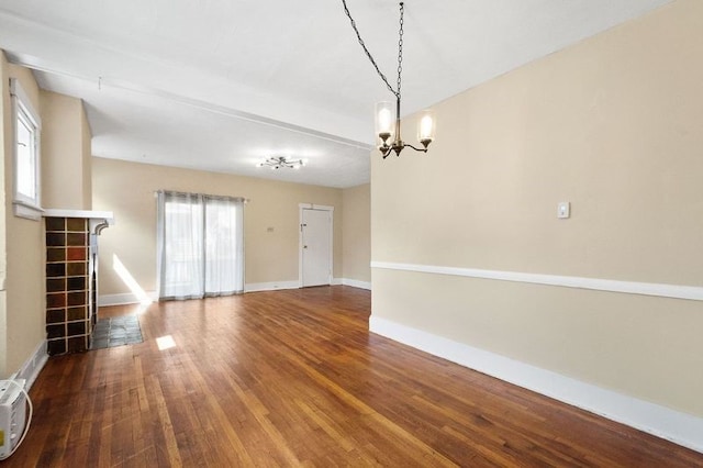 interior space featuring hardwood / wood-style flooring, a tiled fireplace, and a notable chandelier