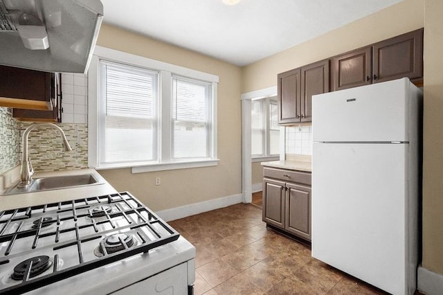 kitchen featuring tile patterned floors, white fridge, sink, stainless steel stove, and ventilation hood