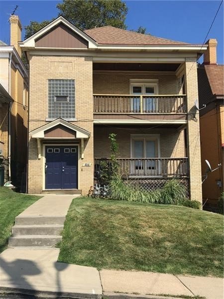 view of front facade featuring a balcony and a front lawn