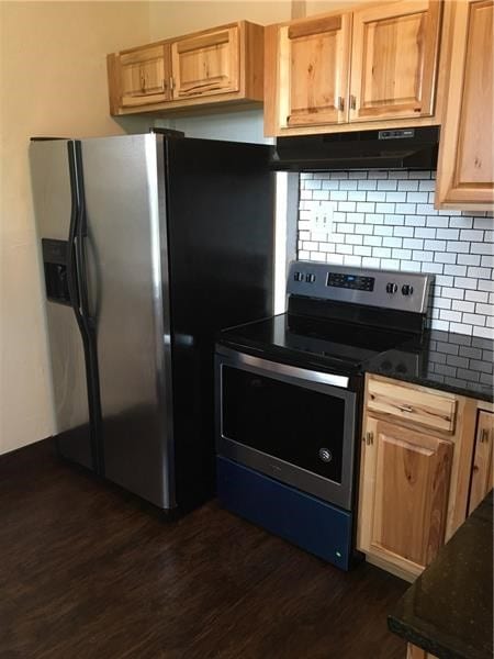 kitchen with dark wood-type flooring, dark stone countertops, stainless steel appliances, and tasteful backsplash