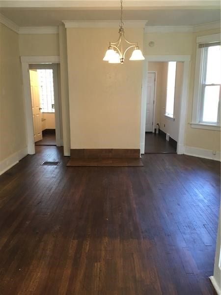 spare room with crown molding, a chandelier, and dark hardwood / wood-style floors