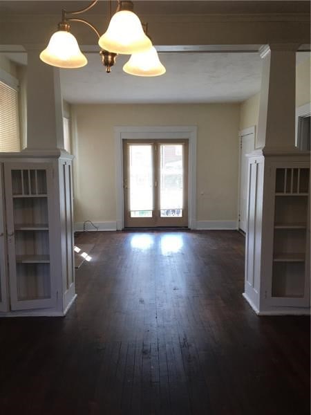 unfurnished living room featuring dark wood-type flooring and an inviting chandelier