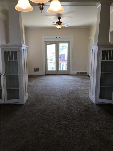 unfurnished living room featuring ceiling fan with notable chandelier, crown molding, and carpet floors