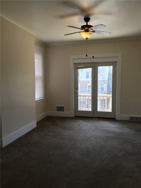 unfurnished room featuring ceiling fan, ornamental molding, and dark colored carpet