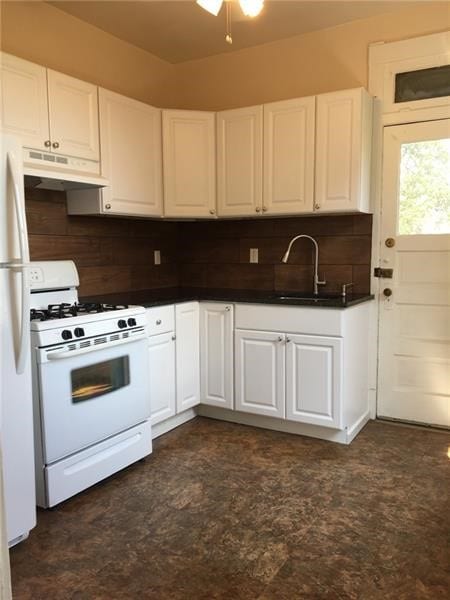 kitchen with backsplash, white appliances, and white cabinets