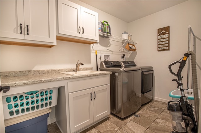 clothes washing area with washer and dryer, cabinets, and sink