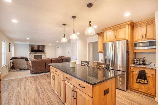 kitchen with a kitchen island, stainless steel appliances, a fireplace, and light hardwood / wood-style flooring