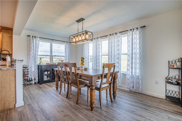 dining space featuring a textured ceiling, wood-type flooring, and a notable chandelier