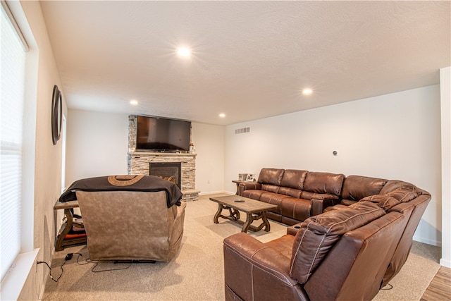 living room featuring light colored carpet, a fireplace, and a textured ceiling