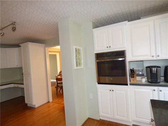 kitchen featuring light hardwood / wood-style flooring, stainless steel oven, and white cabinets