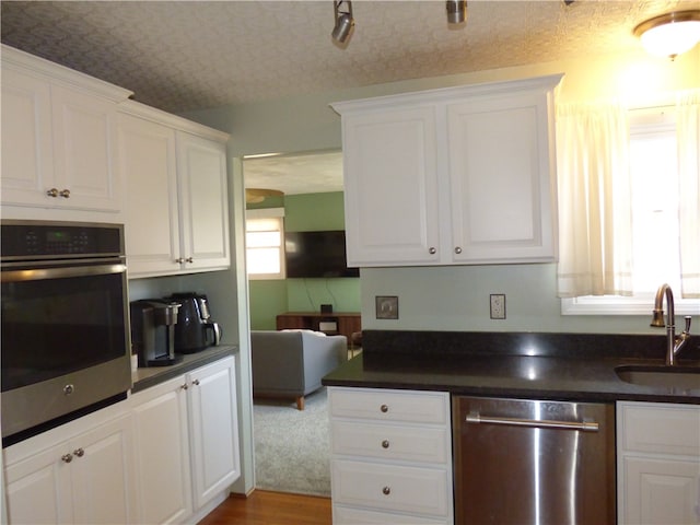 kitchen featuring a wealth of natural light, stainless steel appliances, sink, and white cabinetry