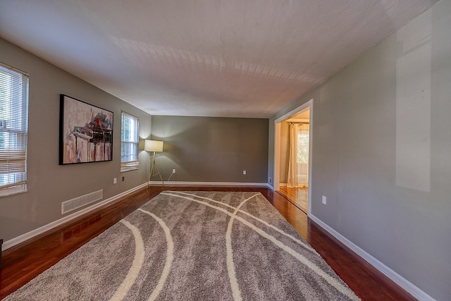 unfurnished room with a healthy amount of sunlight and hardwood / wood-style floors