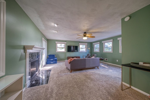 carpeted living room featuring a textured ceiling, ceiling fan, and a high end fireplace