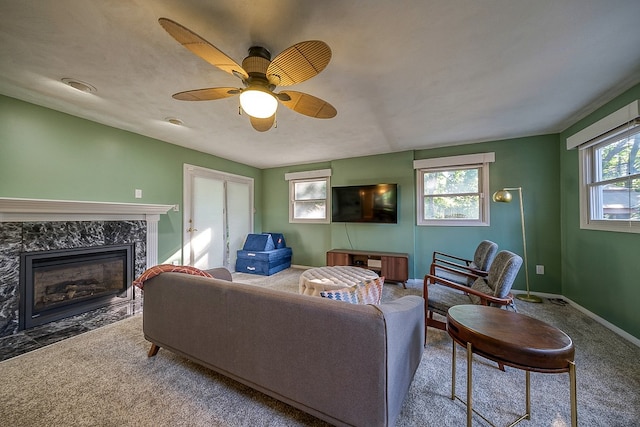 living room with carpet flooring, ceiling fan, a fireplace, and a healthy amount of sunlight