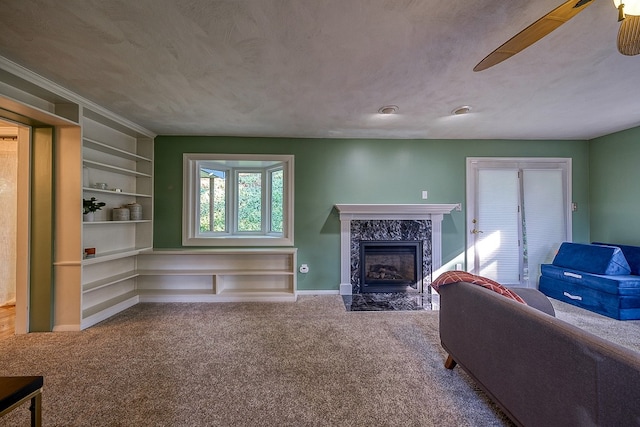 carpeted living room featuring crown molding, a premium fireplace, ceiling fan, and a textured ceiling