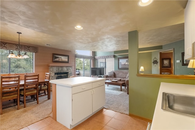 kitchen featuring a fireplace, a chandelier, white cabinetry, kitchen peninsula, and pendant lighting