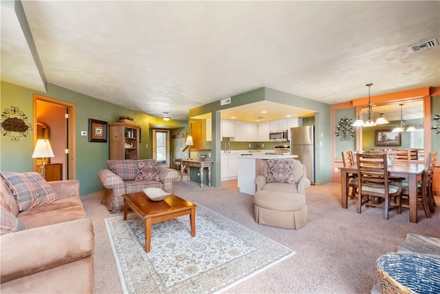 living room with light colored carpet, sink, and a chandelier