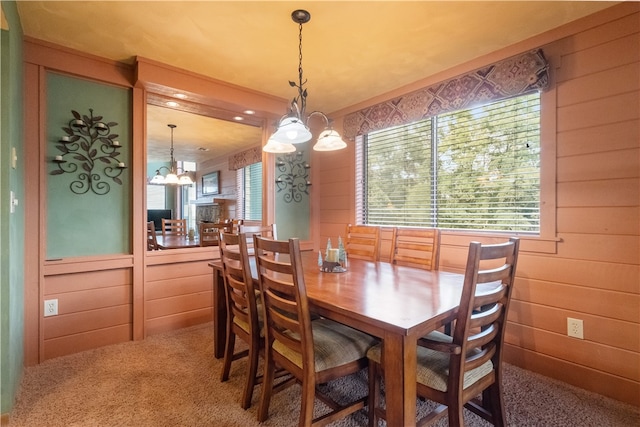 carpeted dining area featuring wooden walls and a chandelier