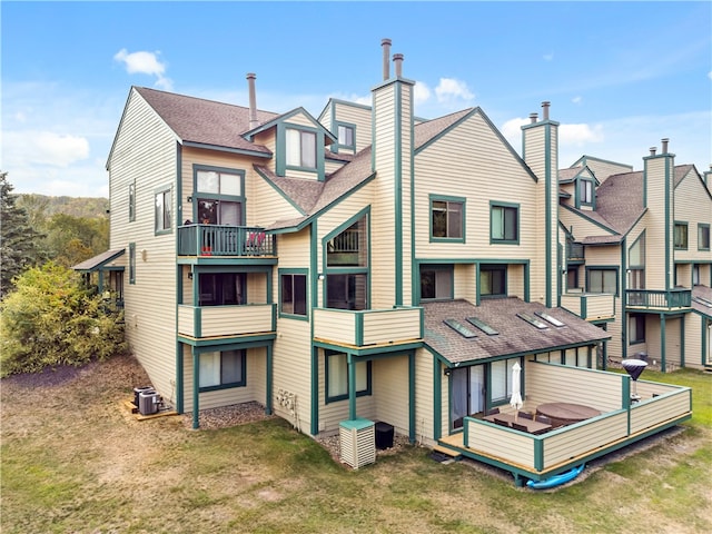 back of property with a balcony, a jacuzzi, a lawn, and cooling unit