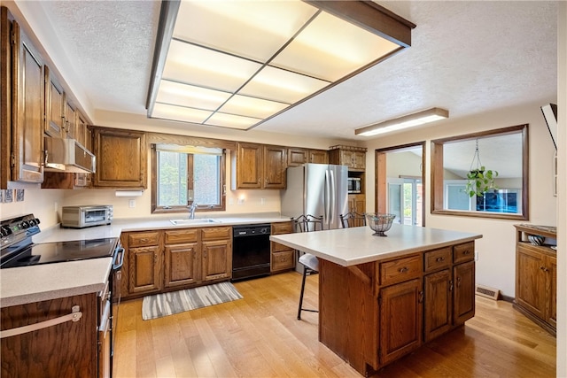 kitchen featuring black dishwasher, a center island, sink, light wood-type flooring, and stainless steel range with electric cooktop