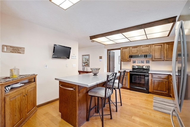 kitchen featuring a kitchen island, black range with electric stovetop, stainless steel refrigerator, and light hardwood / wood-style flooring