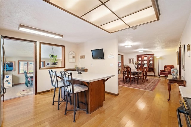 kitchen featuring range, a textured ceiling, a breakfast bar, and light hardwood / wood-style floors