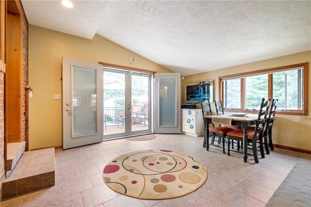 tiled dining space featuring vaulted ceiling, a textured ceiling, plenty of natural light, and french doors