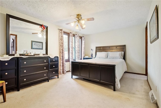 bedroom with a textured ceiling, light colored carpet, and ceiling fan