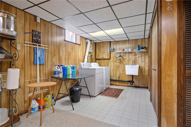 laundry area featuring wood walls, washer and dryer, and sink