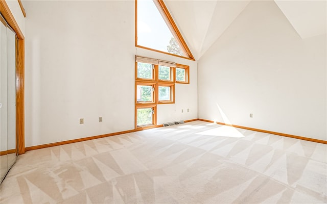 spare room with light colored carpet and high vaulted ceiling