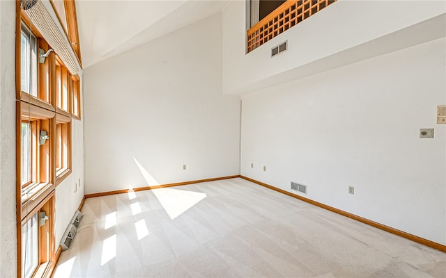 carpeted empty room with a baseboard radiator and a towering ceiling