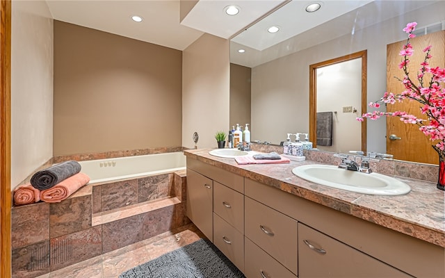 bathroom with vanity and tiled tub