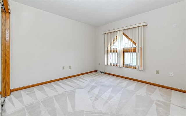 spare room featuring baseboard heating and light carpet