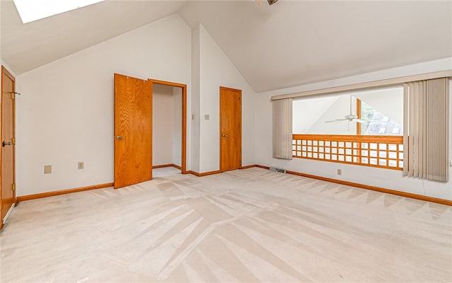 bonus room with ceiling fan, light carpet, and vaulted ceiling with skylight