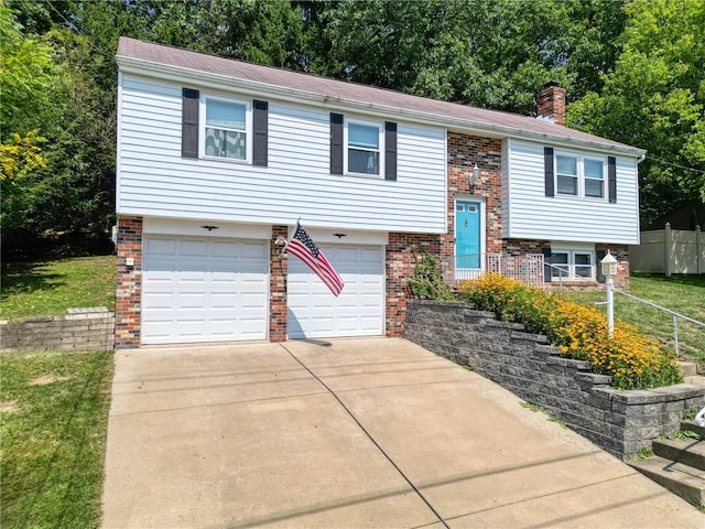 split foyer home featuring brick siding, a chimney, fence, a garage, and driveway