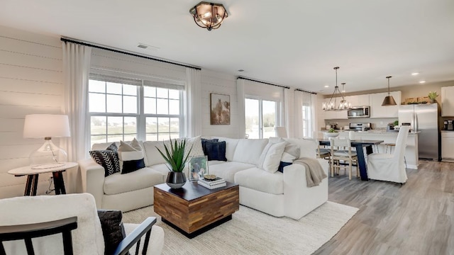 living room featuring wood walls, a healthy amount of sunlight, and light wood-type flooring