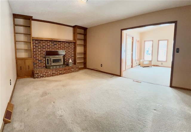 unfurnished living room with built in features, carpet floors, and a wood stove