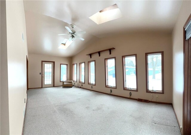 spare room featuring ceiling fan, light colored carpet, and lofted ceiling with skylight