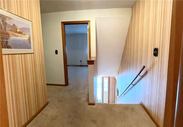 corridor featuring carpet, a textured ceiling, and wooden walls