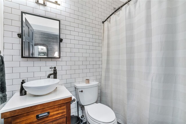 bathroom with tile walls, backsplash, vanity, toilet, and a shower with curtain