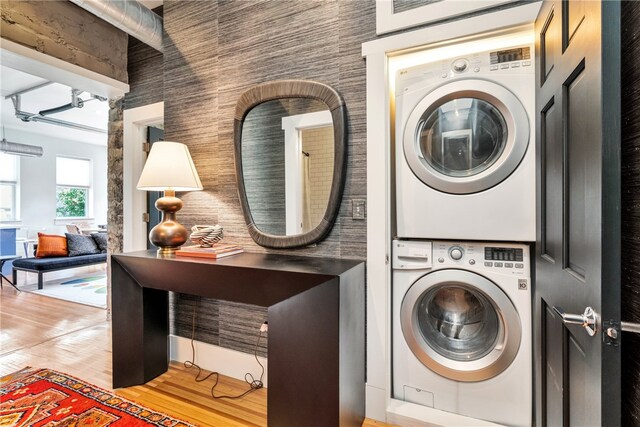 clothes washing area with light wood-type flooring and stacked washer and clothes dryer