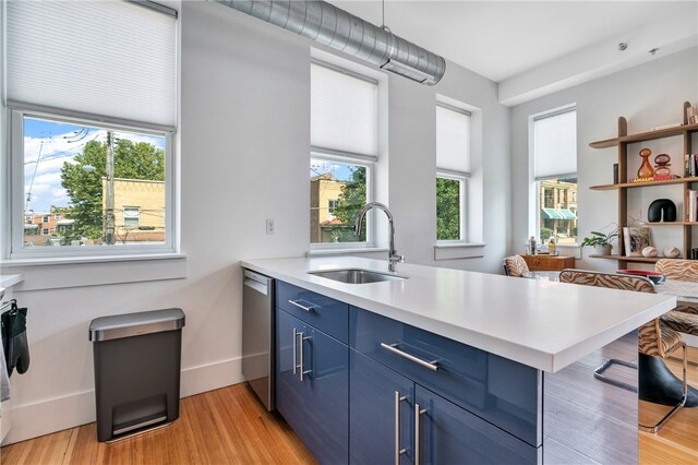 kitchen with light wood-type flooring, sink, blue cabinetry, and plenty of natural light