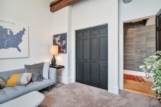 living room featuring carpet floors, a towering ceiling, and beamed ceiling