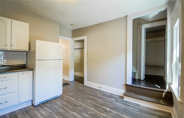 kitchen featuring white cabinets, white refrigerator, a textured ceiling, dark wood-type flooring, and decorative backsplash